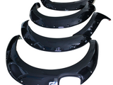 Four glossy black fender flares, arranged in descending size order, are placed against a plain white background, displaying their smooth curved design and attached mounting holes.