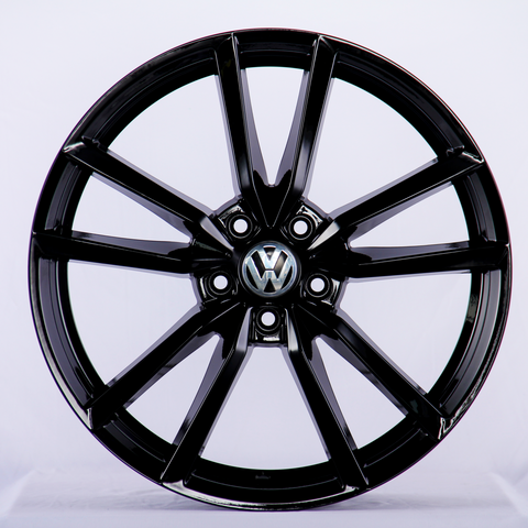 A glossy black alloy wheel with a multi-spoke design, featuring a Volkswagen emblem at the center, set against a plain white background.