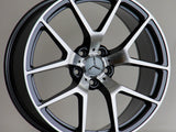 A silver and black Mercedes-Benz AMG alloy wheel rests upright against a neutral background, featuring a five-twin-spoke design and prominent Mercedes emblem at the center.