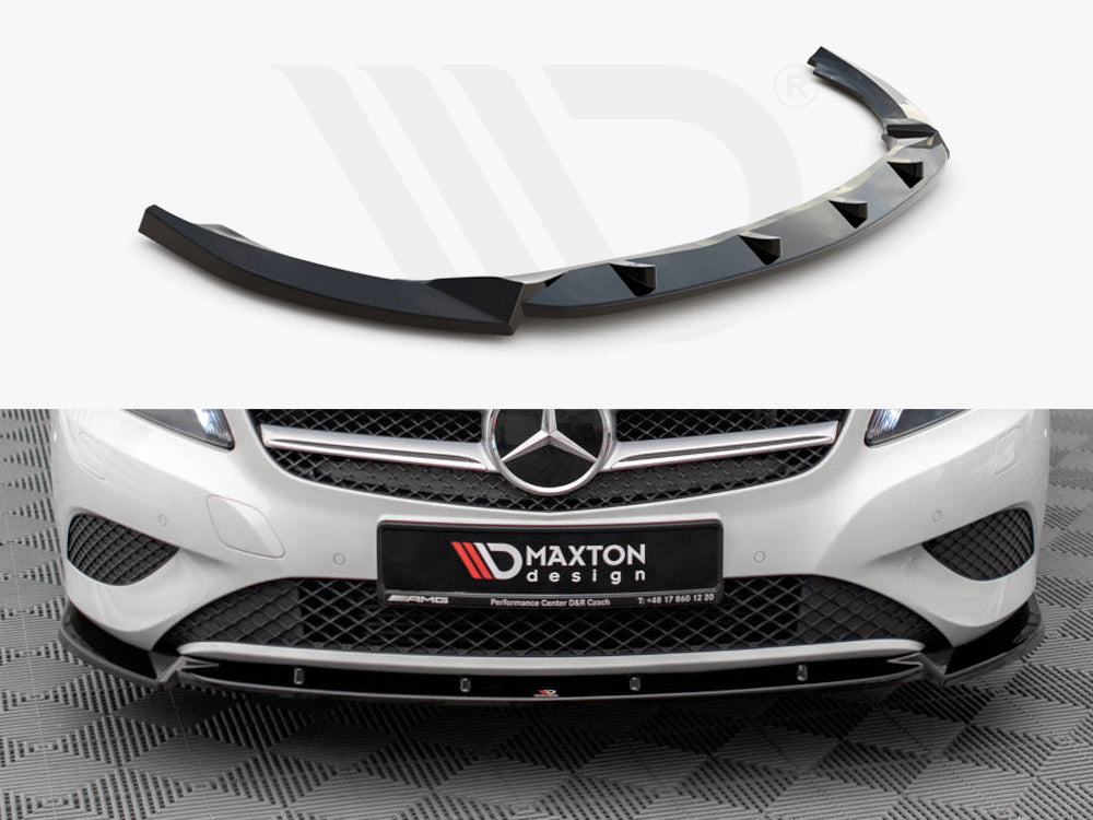 A glossy, black car splitter with angular fins is displayed alone above the grille and bumper of a white Mercedes-Benz in a showroom. License plate reads "MAXTON design."