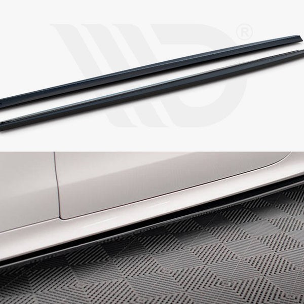 Black side skirts rest above an image of a white car's side panel. The car is parked on a patterned surface, showcasing the accessory's application.