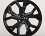 A glossy black car wheel rim with five split spokes, featuring the Audi logo in the center, is displayed against a plain white background.