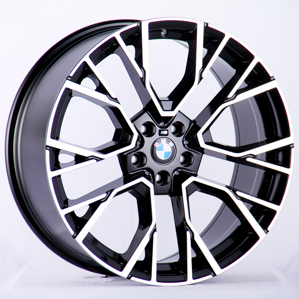 A sleek black and silver alloy wheel with a geometric design, centrally displaying the BMW logo, stands against a plain white background.
