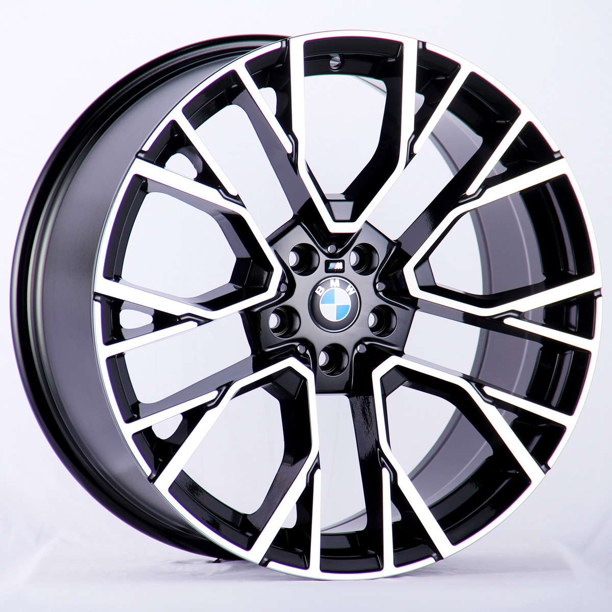 A BMW alloy wheel with a black and silver geometric spoke pattern rests against a white background, featuring the BMW logo at the center.