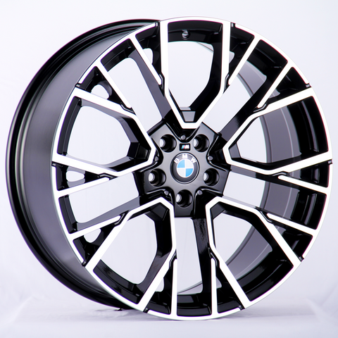 A BMW alloy wheel with a black and silver geometric spoke pattern rests against a white background, featuring the BMW logo at the center.