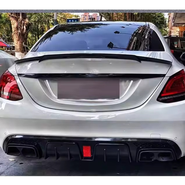 A white car with tinted windows is parked, showcasing a rear spoiler and dual exhausts. It's situated on a street lined with trees and buildings in the background.