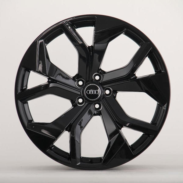 A black, glossy alloy wheel with a five-spoke design, displaying the Audi logo in the center, is positioned against a plain light gray background.