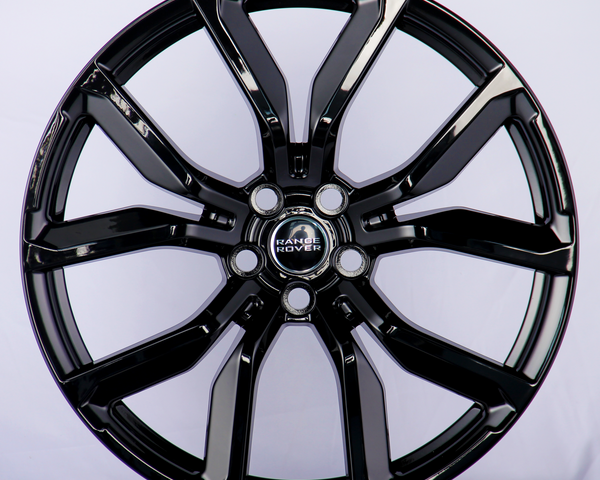 A shiny black alloy wheel features prominent spokes and a "Range Rover" logo at its center, set against a plain white background.