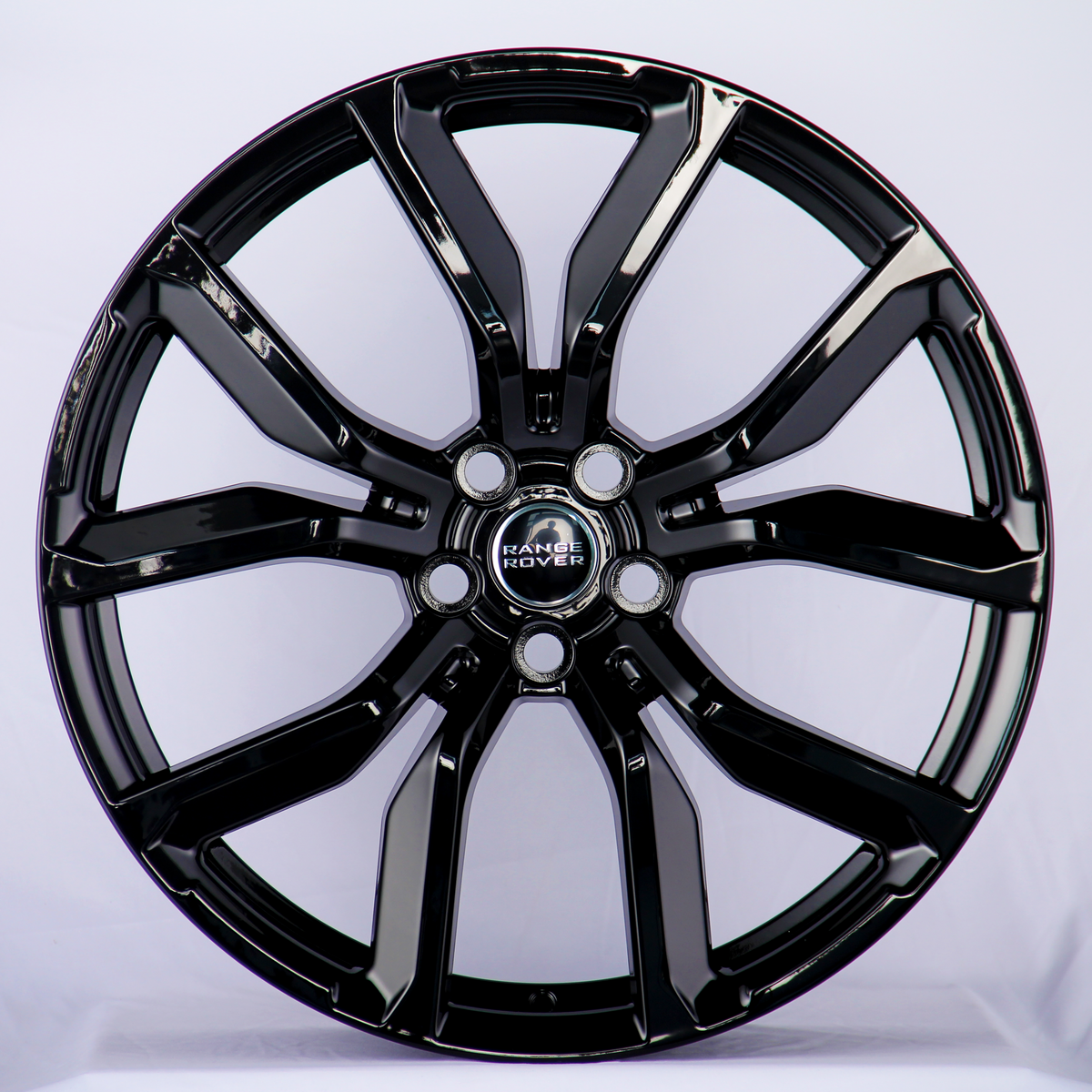 A shiny black alloy wheel features prominent spokes and a "Range Rover" logo at its center, set against a plain white background.