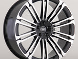 A black and silver Land Rover alloy wheel with multiple spokes is displayed against a plain gray background. The center cap features the 