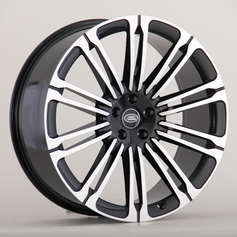 A black and silver Land Rover alloy wheel with multiple spokes is displayed against a plain gray background. The center cap features the "LAND ROVER" logo in white text.