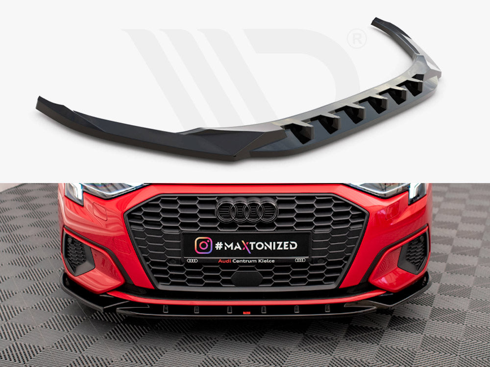 A black car front splitter, designed for aerodynamics, is showcased above a red Audi with a black grille. Below, text reads "#MAXTONIZED" and "Audi Centrum Kielce" on a patterned floor.