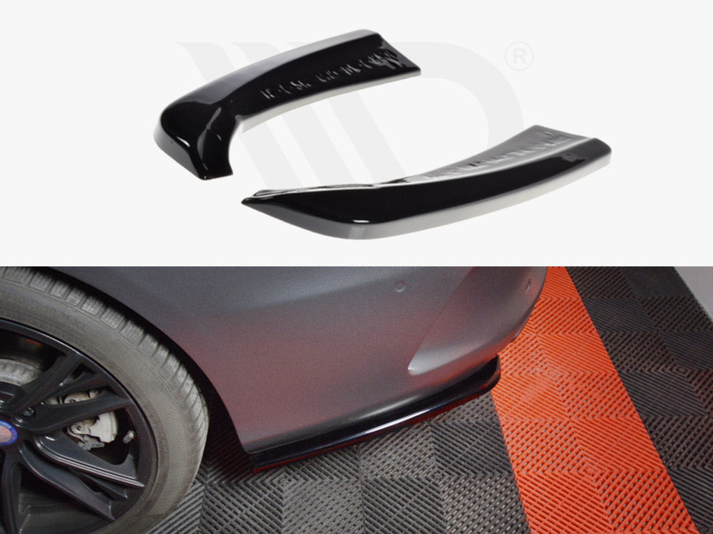 Black car splitters are displayed separately on a white background and installed on a vehicle's rear bumper. The vehicle is on a red and black checkered floor.