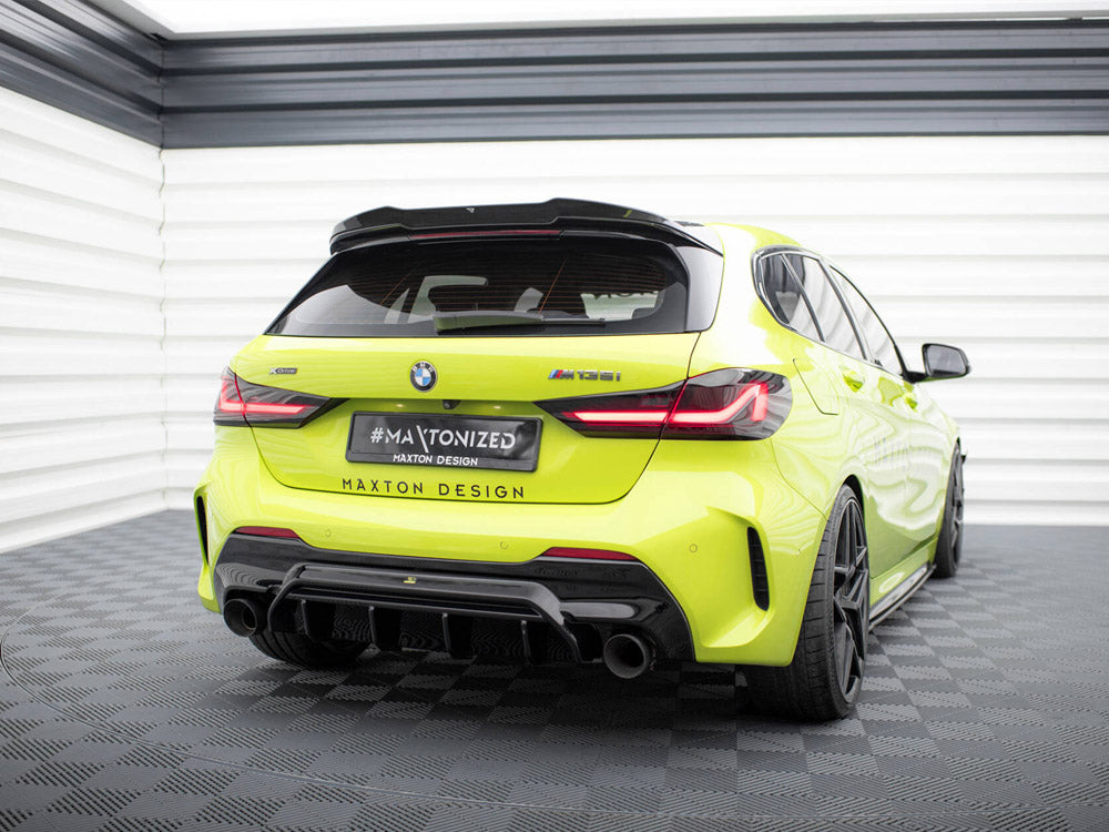 A bright yellow BMW M135i is parked in a white, enclosed garage. The license plate reads "#MAXTONIZED, MAXTON DESIGN", and the car features a sporty rear diffuser and black wheels.