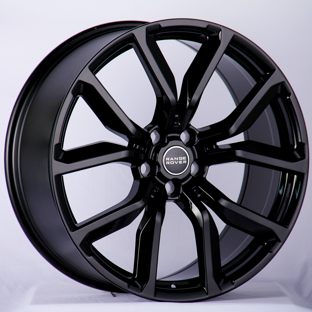 A glossy black alloy wheel featuring the "Range Rover" logo in the center, resting against a neutral background, highlighting its sleek design and intricate spoke pattern.