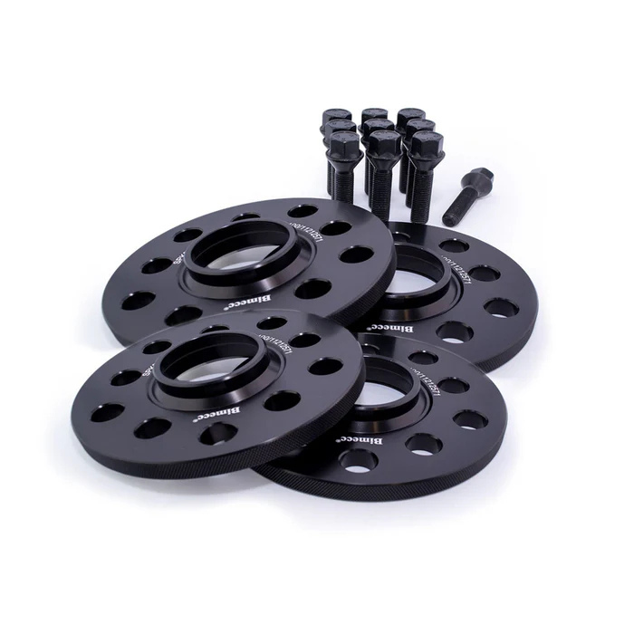 Four black wheel spacers with multiple holes, labeled "Billettec," are arranged in front of several black bolts, placed on a plain white background.
