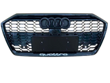 A front car grille displays the Audi logo with four rings and a honeycomb pattern. Below, 
