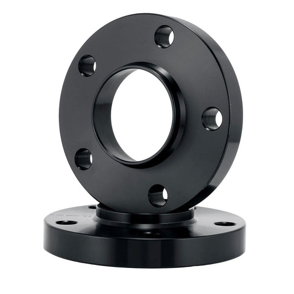 A black metal flange with a central hole and multiple bolt holes sits upright on another similar flange, set against a plain white background.