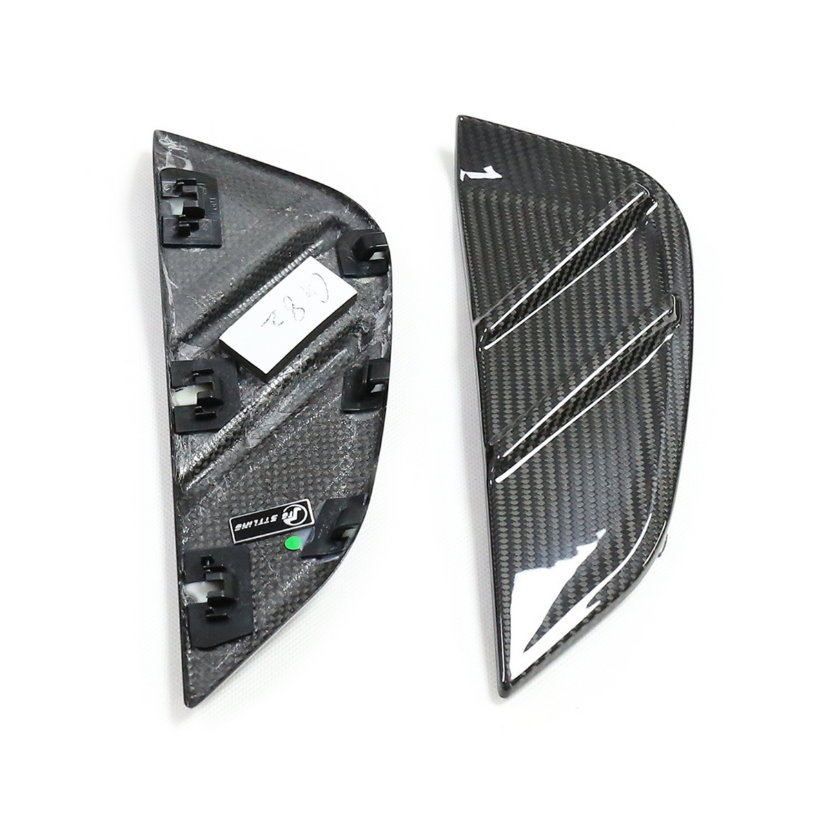 Two carbon fiber car parts are placed side by side; one shows a textured, reflective surface with three grooves, and the other reveals attachment clips. Text reads "G28" and "UF STYLING."