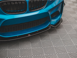 A blue car with a sporty front bumper rests on a patterned floor, featuring a geometric design of interlocking diamond shapes.