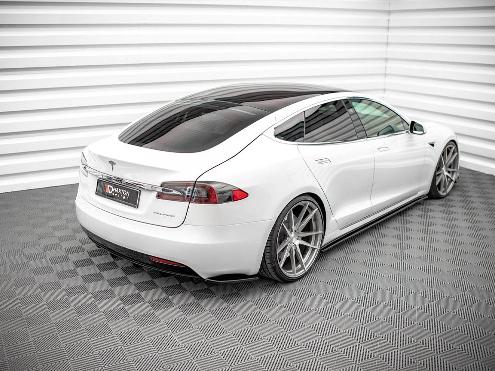 A white car is parked, showcasing large alloy wheels, in a patterned, enclosed setting. A sign on the rear reads "Maxton Design."