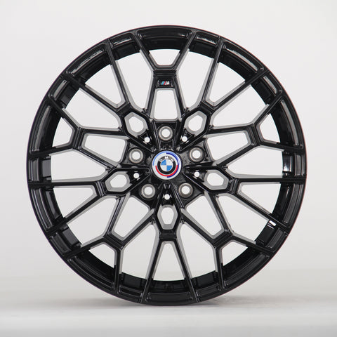 A black multi-spoke alloy wheel is displayed upright, featuring a BMW emblem in the center. The intricate design sits against a plain, light gray backdrop.