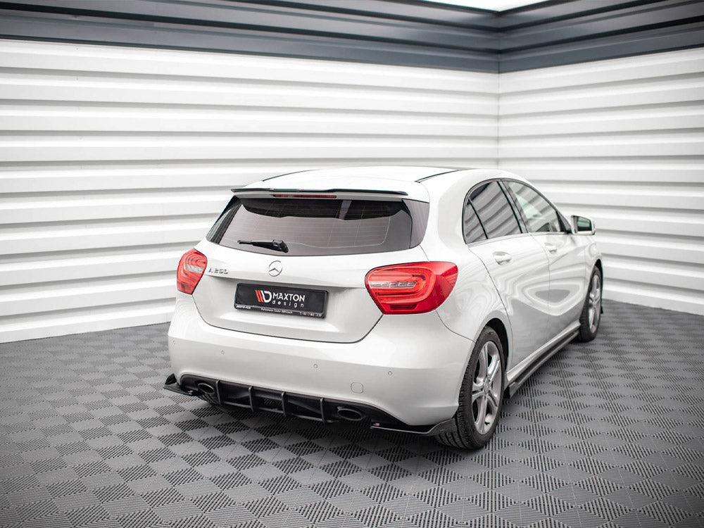 A white Mercedes-Benz A 180 d is parked in a modern, bright showroom with textured gray flooring and a striped white wall. A rear license plate reads "Maxton design."