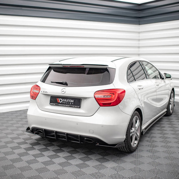 A white Mercedes-Benz A 180 d is parked in a modern, bright showroom with textured gray flooring and a striped white wall. A rear license plate reads "Maxton design."