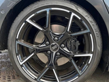A black Audi car wheel with intricate silver spokes is parked on a concrete surface. The tire reads 