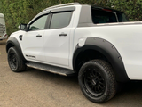 White pickup truck, parked, features black wheel arches and step bars; 