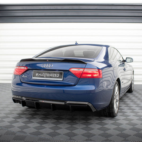 Blue Audi A5 parked in a garage with checkered flooring and white walls. The rear view shows a "#MAXTONIZED" license plate.