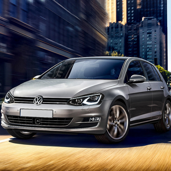 A silver Volkswagen car moves swiftly on a road, with blurred city skyscrapers in the background, conveying speed and urban environment.