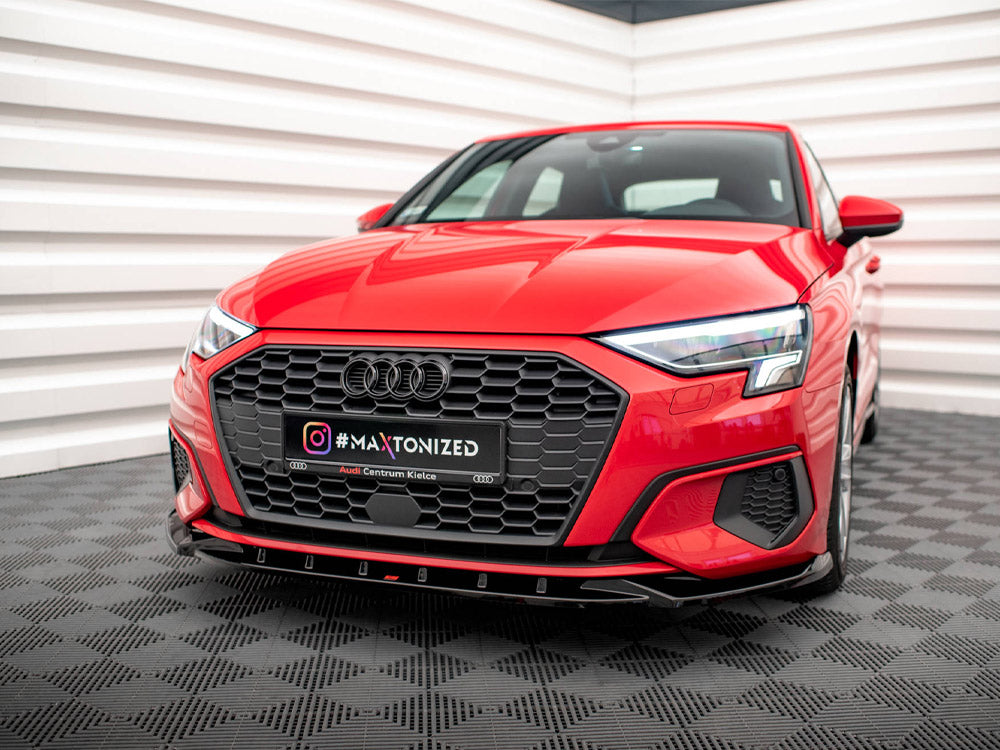 A red car is stationary in a showroom with textured flooring and white paneled walls. The license plate reads "#MAXTONIZED Audi Centrum Kielce" alongside the Instagram logo.