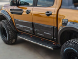 A modified pickup truck, parked, displaying a shiny orange and black exterior with large off-road tires labeled 