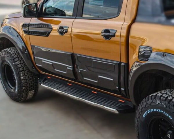 A modified pickup truck, parked, displaying a shiny orange and black exterior with large off-road tires labeled "BFGoodrich" and distinct side steps; situated on a paved surface.