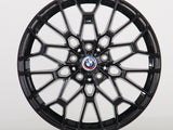 A glossy black, intricately designed car wheel with a central BMW logo and 