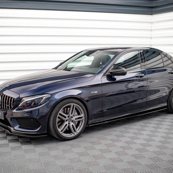 A dark blue sedan, parked on patterned flooring, features sleek design and five-spoke alloy wheels. The backdrop consists of angled, white metal walls with a modern, industrial style.