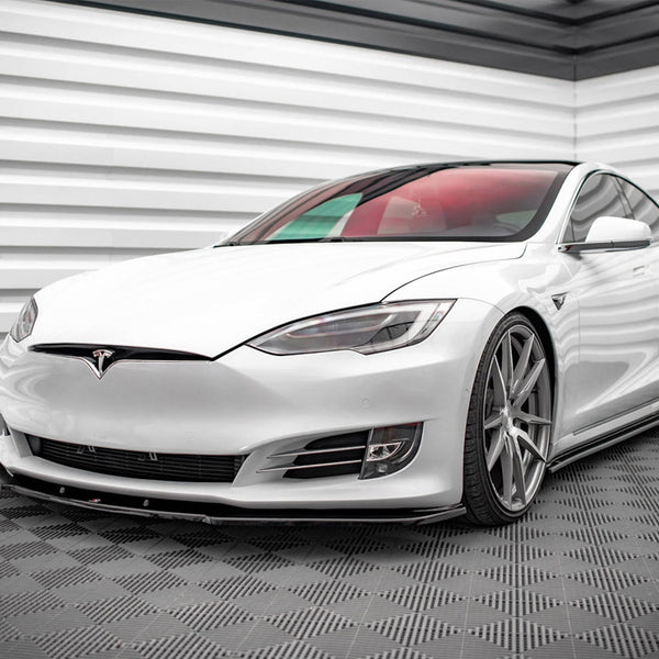 A white Tesla car is parked in a minimalistic garage with patterned flooring and textured white walls, emphasizing its sleek and modern design.