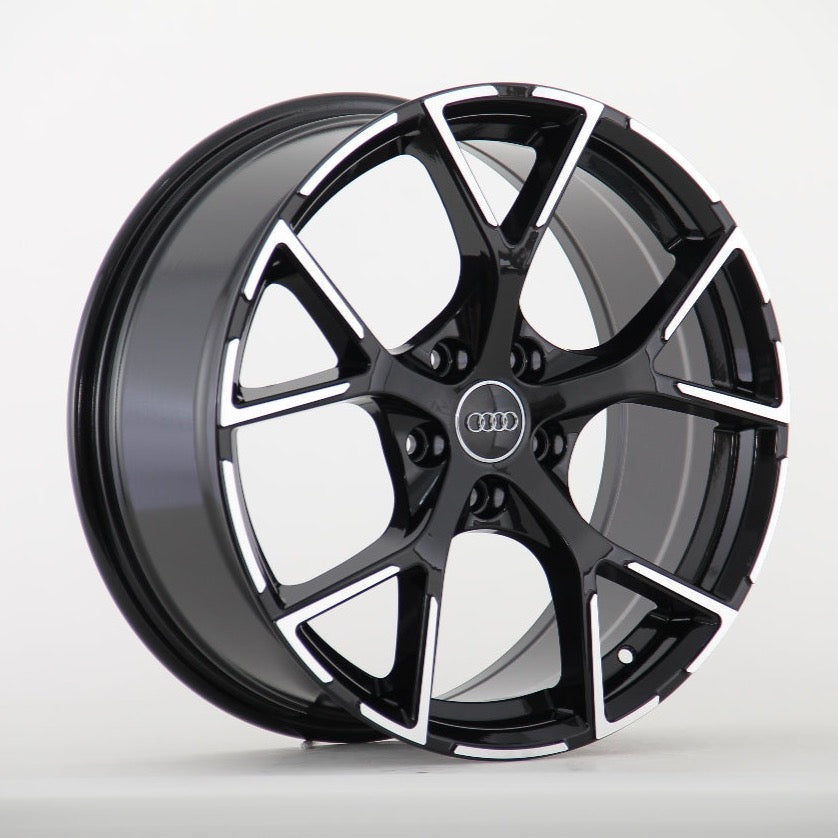A glossy black alloy wheel with a five-spoke pattern, featuring the Audi logo at the center, displayed against a plain white background.