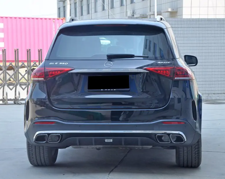 A black Mercedes SUV, labeled "GLE 350" and "4MATIC," is parked in an urban area with a building and a pink shipping container in the background.