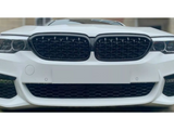 A white car with a prominent front grille and headlights is parked outdoors, facing the viewer. The grille features a black mesh design, framed by a sleek body.