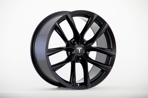 A sleek black alloy wheel is displayed upright, featuring a multi-spoke design with the Tesla logo at its center, set against a plain white background.