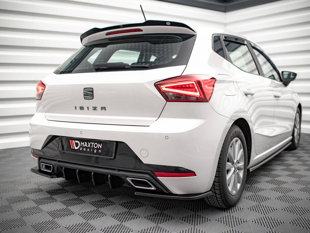 A white car is parked indoors on a checkered floor, showcasing its rear with red taillights illuminated. Text reads "IBIZA" and "Maxton Design" on the bumper panel.