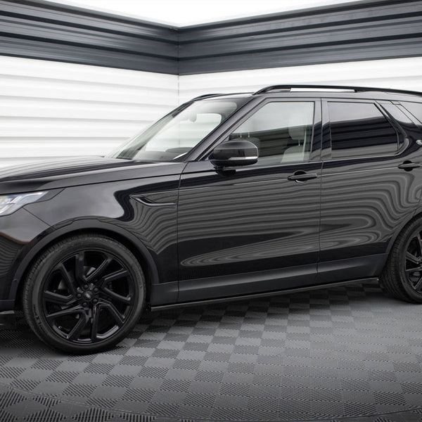 A black SUV is parked in a garage with checkered flooring and striped walls, reflecting light off its glossy surface.