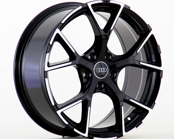 A glossy black alloy wheel with a five-spoke design is standing upright. It features the Audi logo at the center, against a plain white background.