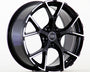 A glossy black alloy wheel with a five-spoke design is standing upright. It features the Audi logo at the center, against a plain white background.