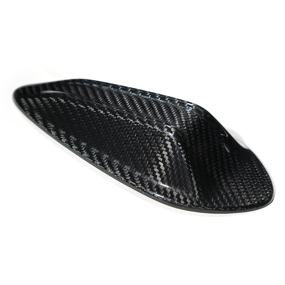 A sleek, black carbon fiber object sits on a white background, showcasing a smooth, aerodynamic shape with a woven texture, possibly designed for vehicle use or aerodynamics.