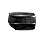 A carbon fiber car part with two horizontal slits, resembling a vent or louver, set against a plain white background.