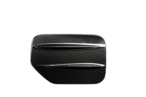 A carbon fiber car part with two horizontal slits, resembling a vent or louver, set against a plain white background.
