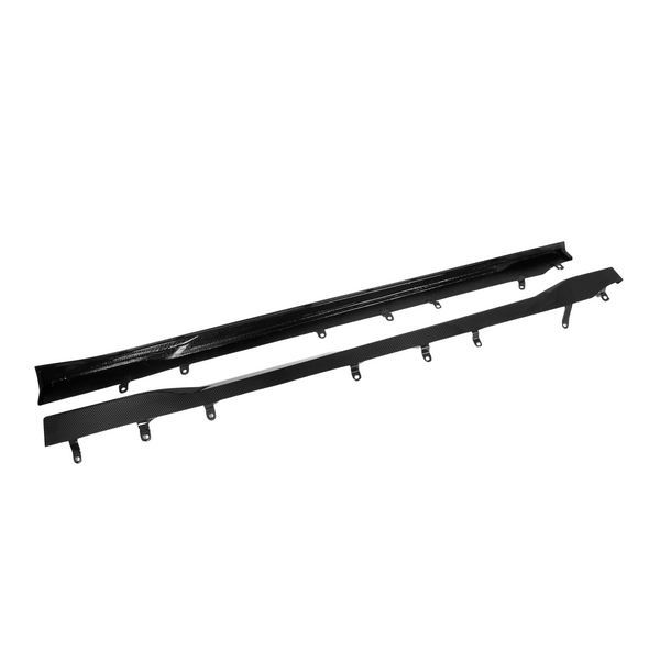 Two black, elongated car side skirts with attachment brackets lie parallel on a white background. The top one is glossy and smooth, while the bottom one has a carbon fiber texture.